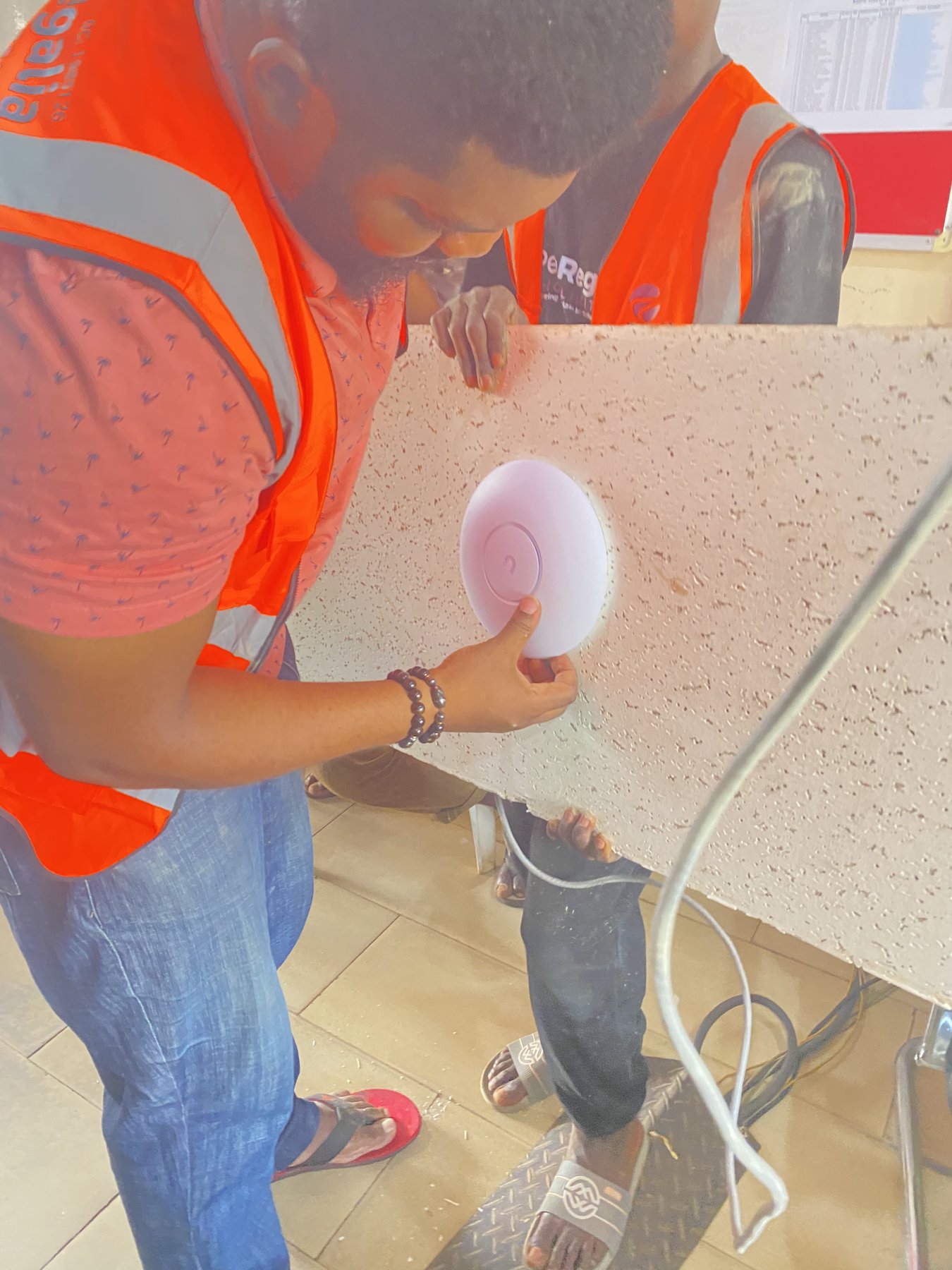 A close-up of the access point being fitted to the ceiling panel.